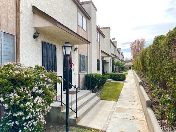Front view of a row of two-story townhouses with steps leading to each entry.