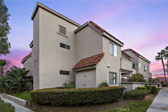 Front view of a multi-story residential building with beige exterior and red-tiled roof.