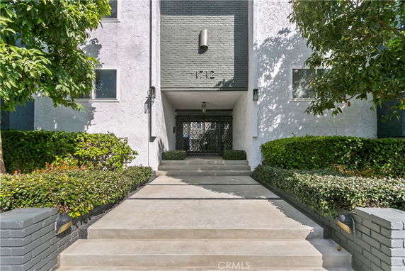 Front view of an apartment building with a landscaped entrance.