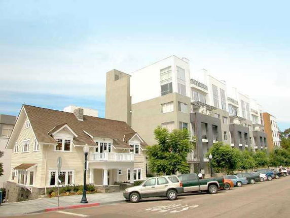 Front view of a traditional house next to a modern multi-story building.