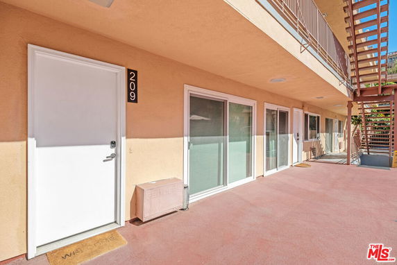 Exterior view of apartment building with doors and windows on the second floor.