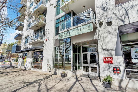 Front view of a modern multi-story building with glass balconies and entrance.