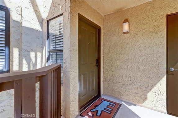 Front view of a house entrance with a brown door and textured walls.