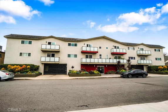 Front view of a three-story apartment building with balconies and a central entrance.