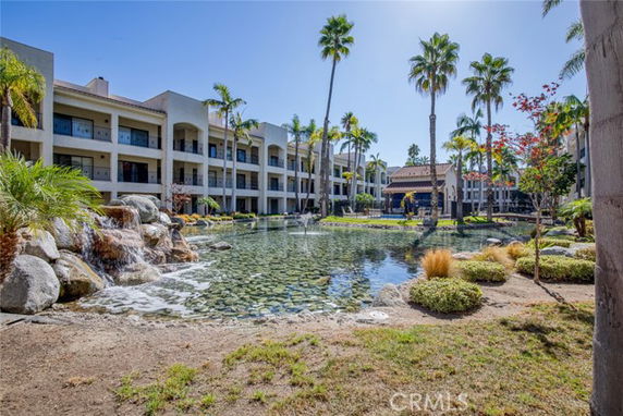 View of a multi-story building complex with a pond and waterfall feature in the courtyard.