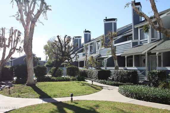 Front view of a multi-story residential building with porches and chimneys.