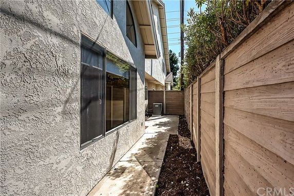 Side view of a house showing exterior wall with windows and adjacent wooden fence