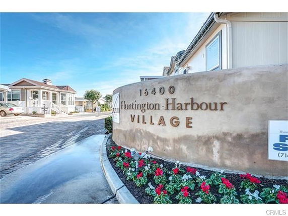 Front view of a residential community entrance with a sign for Huntington Harbour Village.