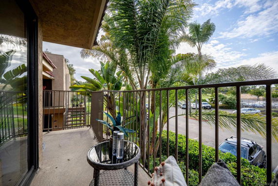 View from a balcony showing a parking area and lush greenery.