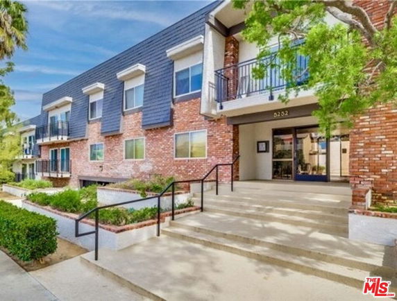 Front view of a multi-story apartment building with brick facade and balconies.