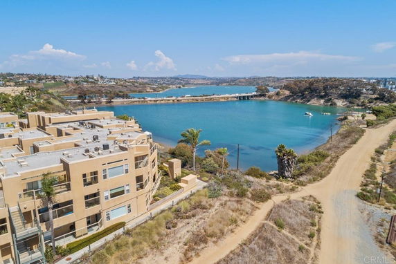Aerial view of a large apartment building near a body of water with scenic surroundings.