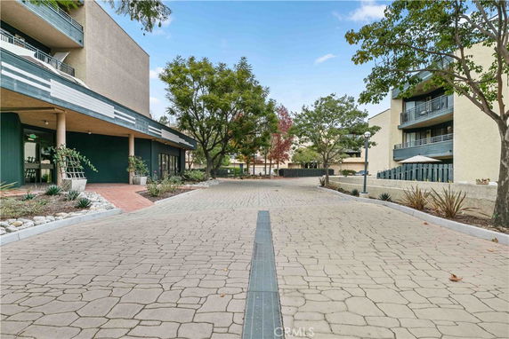 Front view of a modern multi-story building with balconies and a landscaped walkway.