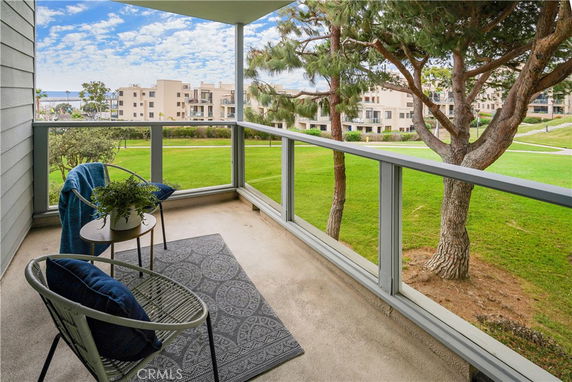 Balcony view of green lawn and trees with buildings in the distance.