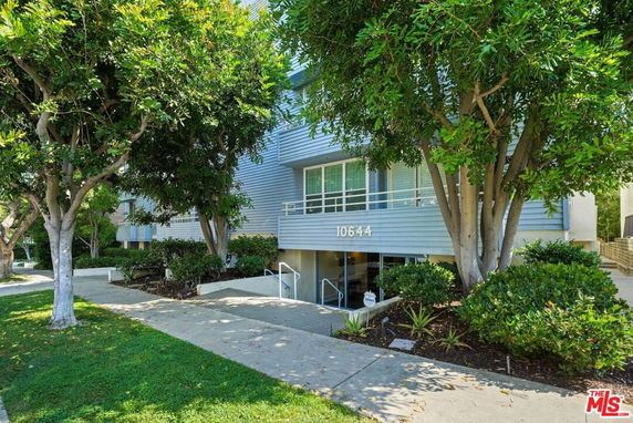 Front view of a residential building with a small entrance and surrounding greenery.