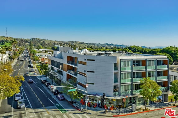 Front view of a modern multi-story building on a busy city street corner.