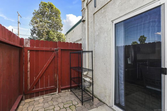 Small outdoor area with a red wooden fence and a glass sliding door.