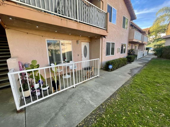 Front view of an apartment building with balconies and a small patio area.