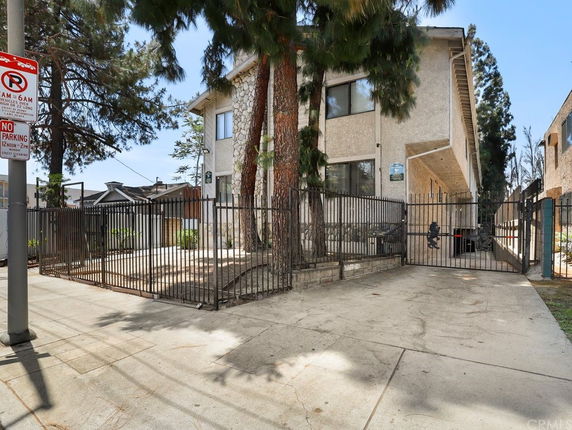 Front view of a multi-story building with gates and fencing.