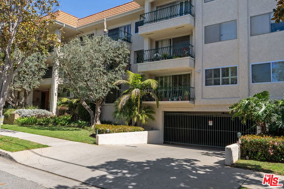 Front view of a multi-story residential building with balconies and a gated entrance.
