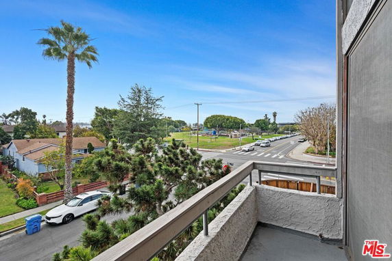 Panoramic view from a balcony overlooking a street intersection with cars and trees.