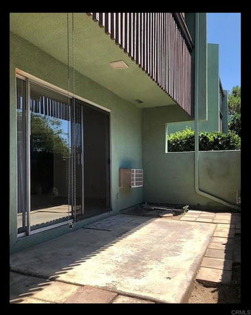 Outdoor patio area with sliding glass door and surrounding walls.