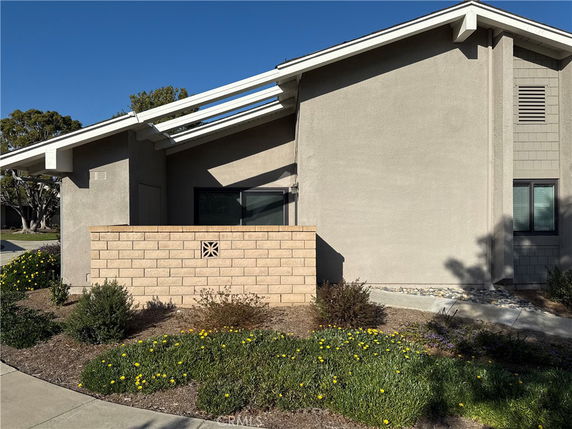 Front view of a modern single-story house with a brick wall in front.
