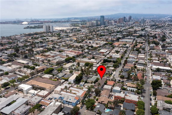 Panoramic view of a coastal city with numerous buildings and roads, a water body in the background, and a marked location within a residential area.