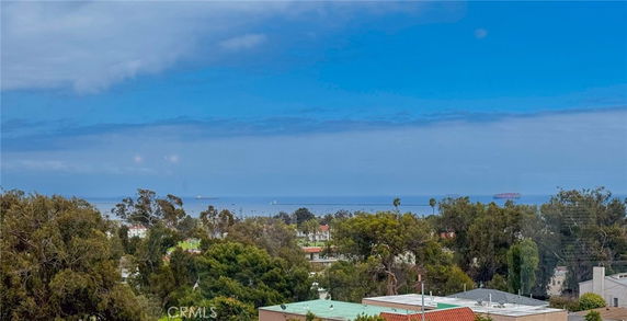 Wide view of surrounding area with trees and ocean visible in the distance under a blue sky.