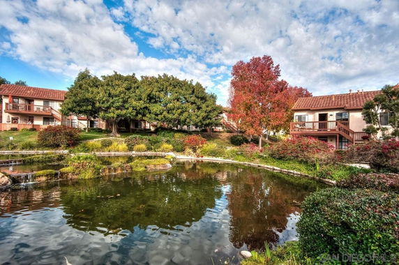 Scenic view of residential buildings surrounded by greenery and a pond.