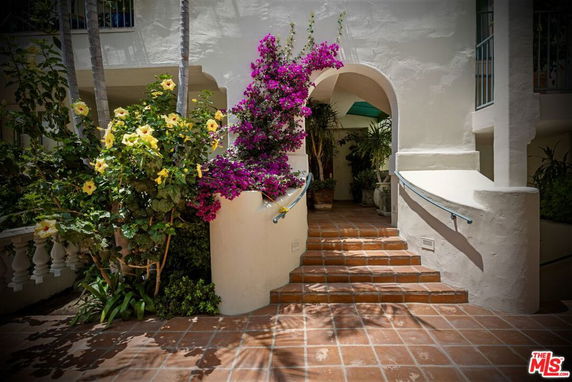 Front view of a building entrance with stairs and floral decor.