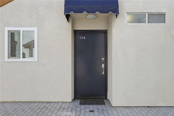 Front view of a building entrance with a dark door marked 104 and a small window.