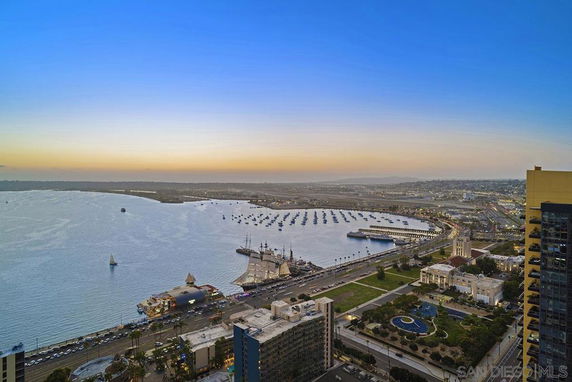 Panoramic view of a coastal area with city structures, waterfront, and boats docked in the marina.