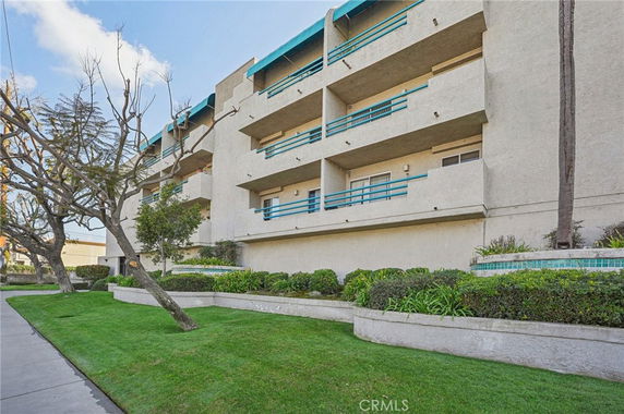 Front view of a multi-story building with balconies and blue railings.