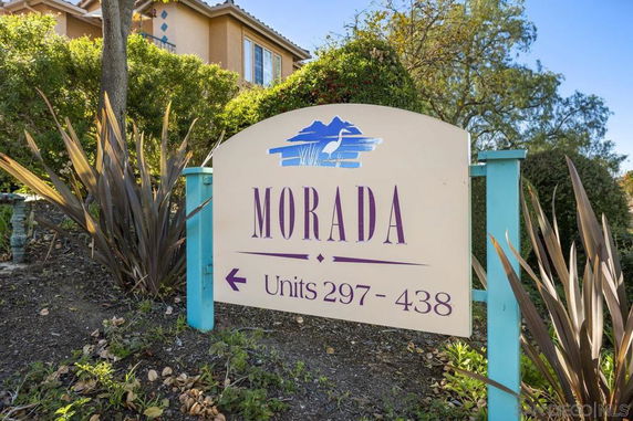A sign with the name 'Morada' and unit numbers 297-438, set in a landscaped area with plants and trees.