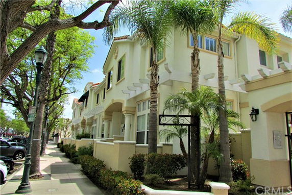 Exterior view of a multi-story residential building with palm trees lining the sidewalk.