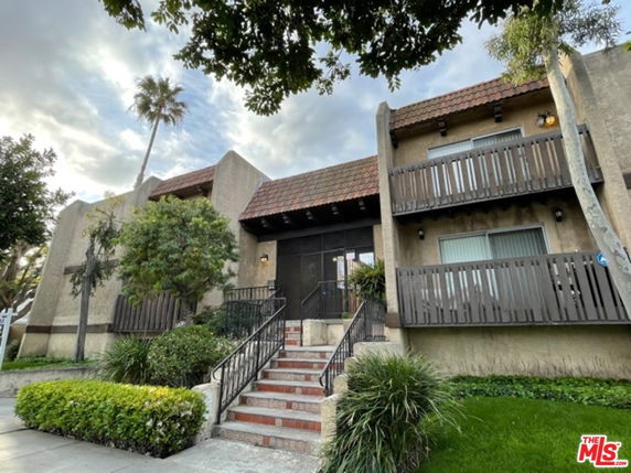 Front view of a two-story building with balconies and a central entrance staircase.