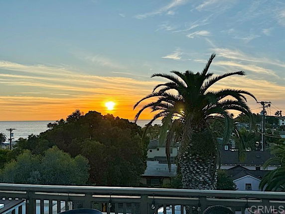 Wide angle view of a sunset over a coastal area with palm trees.