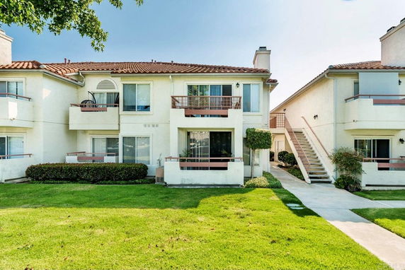 Front view of a two-story residential building with balconies and a tiled roof.