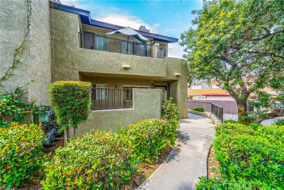 Front view of a multi-story residential building with balconies and a walkway.