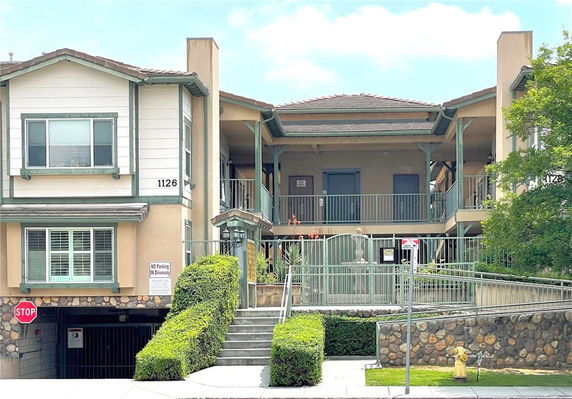 Front view of a two-story residential building with outer staircases and a gated entrance.