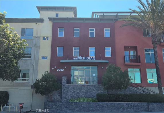 Front view of a multi-story building with a red facade and large glass entrance.