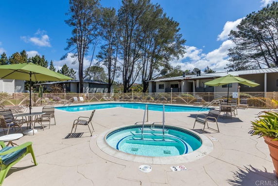 Outdoor swimming pool area with lounge chairs and umbrellas.