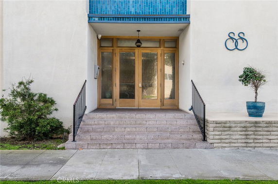 Front view of an entrance with steps leading to double wooden doors.