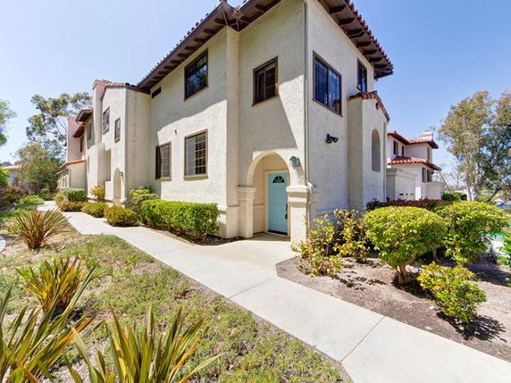 Front view of a multi-story house with a tiled roof and arched entrance.