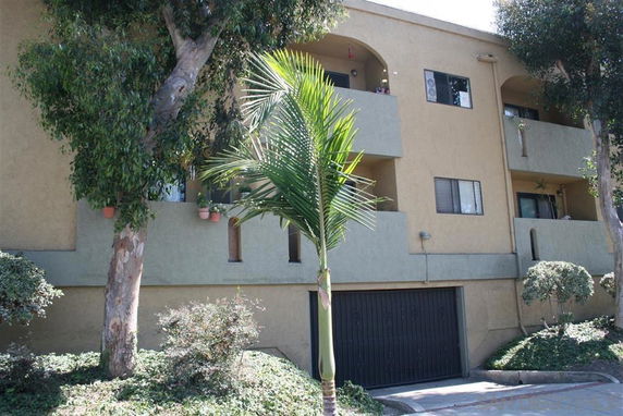 Front view of a multi-story building with balconies and a garage entrance.
