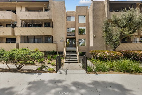 Front view of a multi-story building with balconies and central entrance staircase.