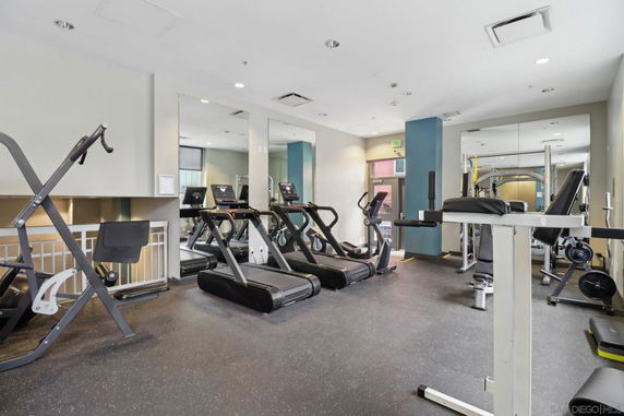Indoor gym area with exercise equipment including treadmills, weight machines, and mirrors.