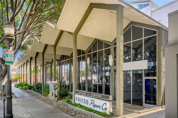 Front view of a commercial building with large glass windows and a distinctive roof design.