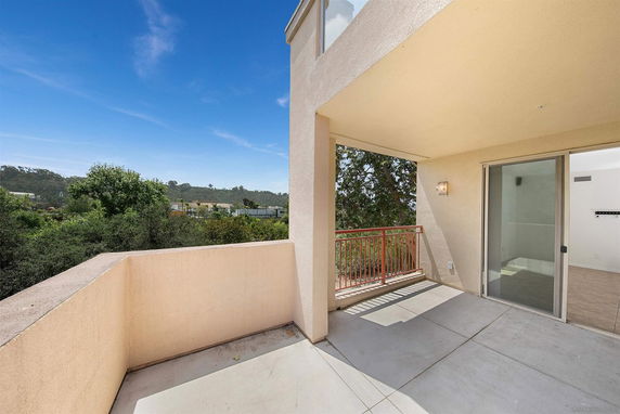 View from a balcony overlooking a green landscape and distant buildings.