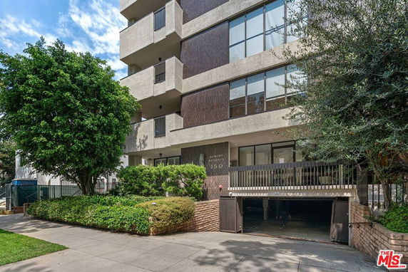 Front view of a multi-story building with balconies and a garage entrance.